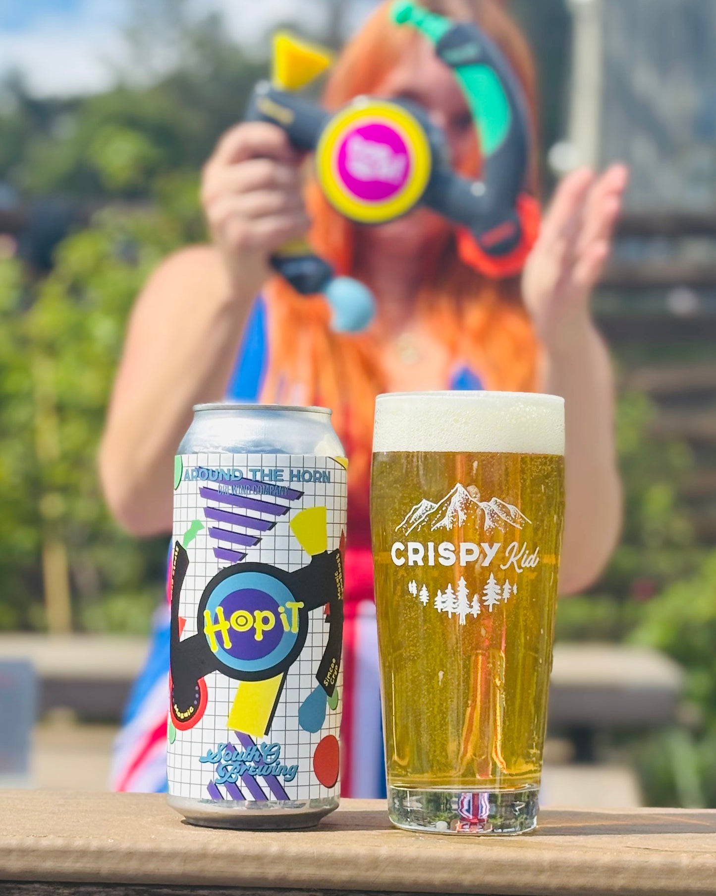 A can and pint of glass of Hop It with a Bop It toy in the background held by someone dressed up as Ginger Spice from the Spice Girls