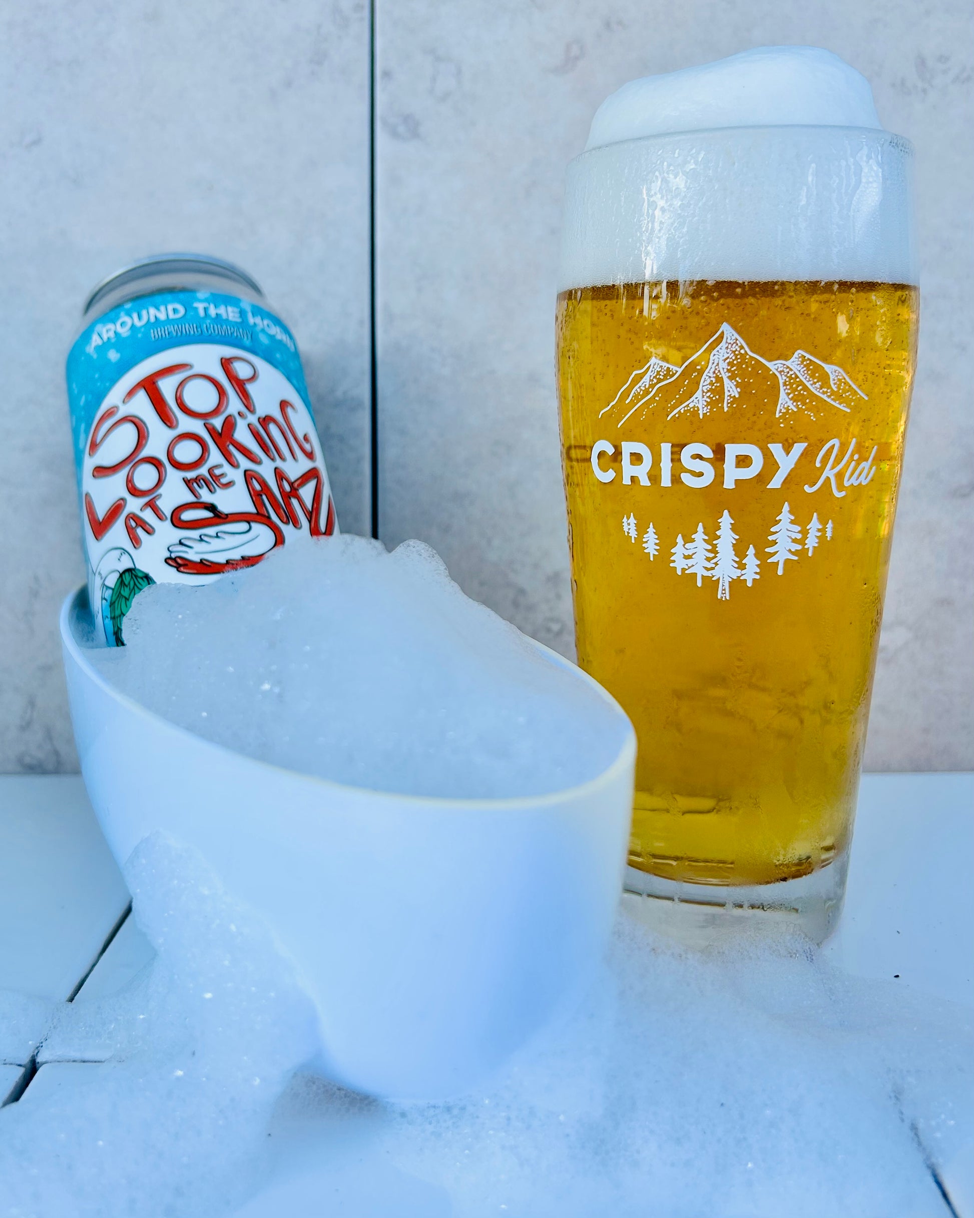 Beer can and glass with a bubble-filled mini bath tub.