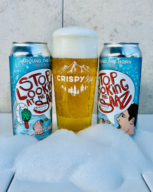 Two cans of beer with artistic labels and a glass of beer in the middle on a bubbly surface.