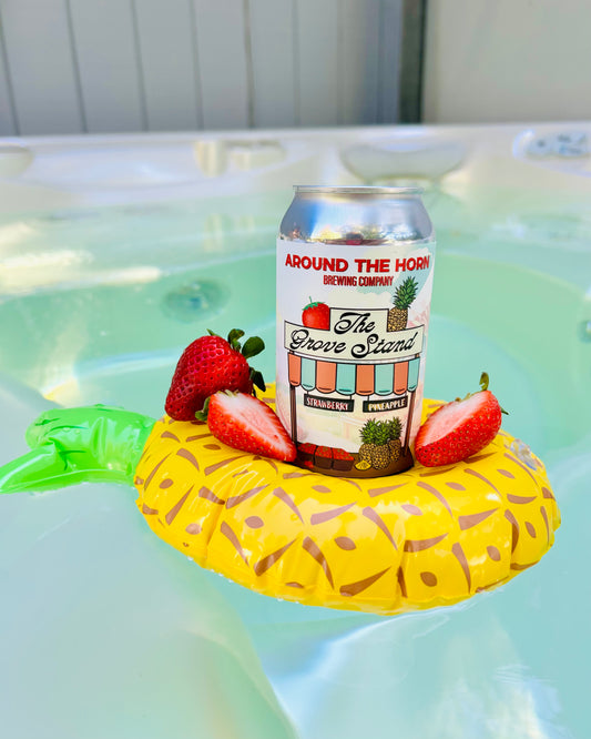 Can of 'Around the Horn Brewing Company' beer on a pineapple-shaped float with strawberries in a hot tub.