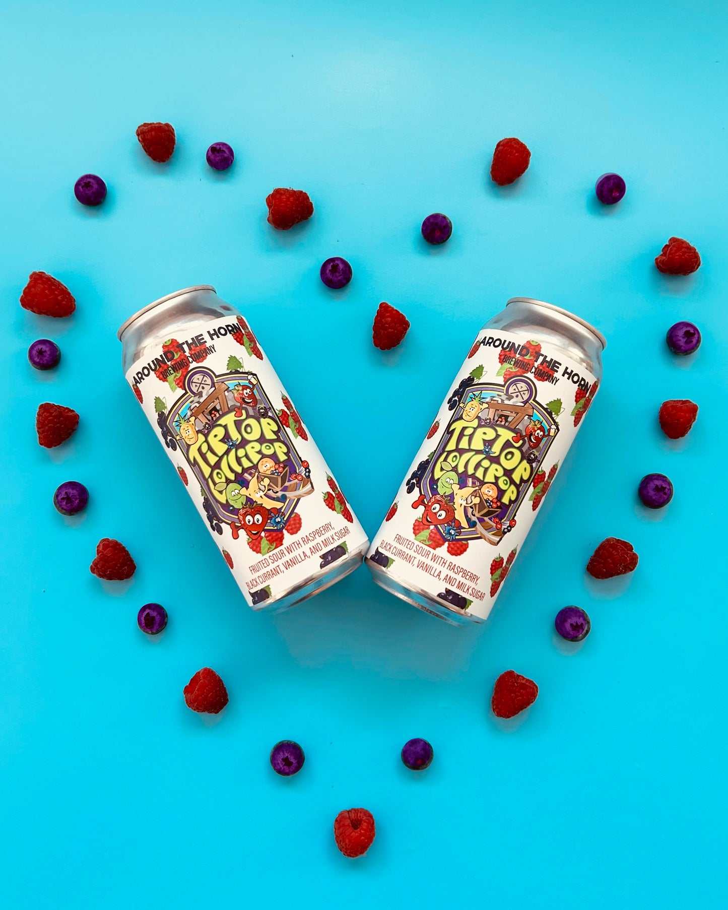 Two cans of Tip Top Lollipop beer surrounded by raspberries and black currants on a blue background